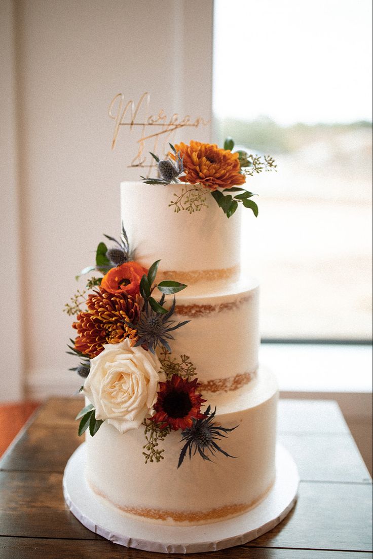 a three tiered wedding cake with flowers on top