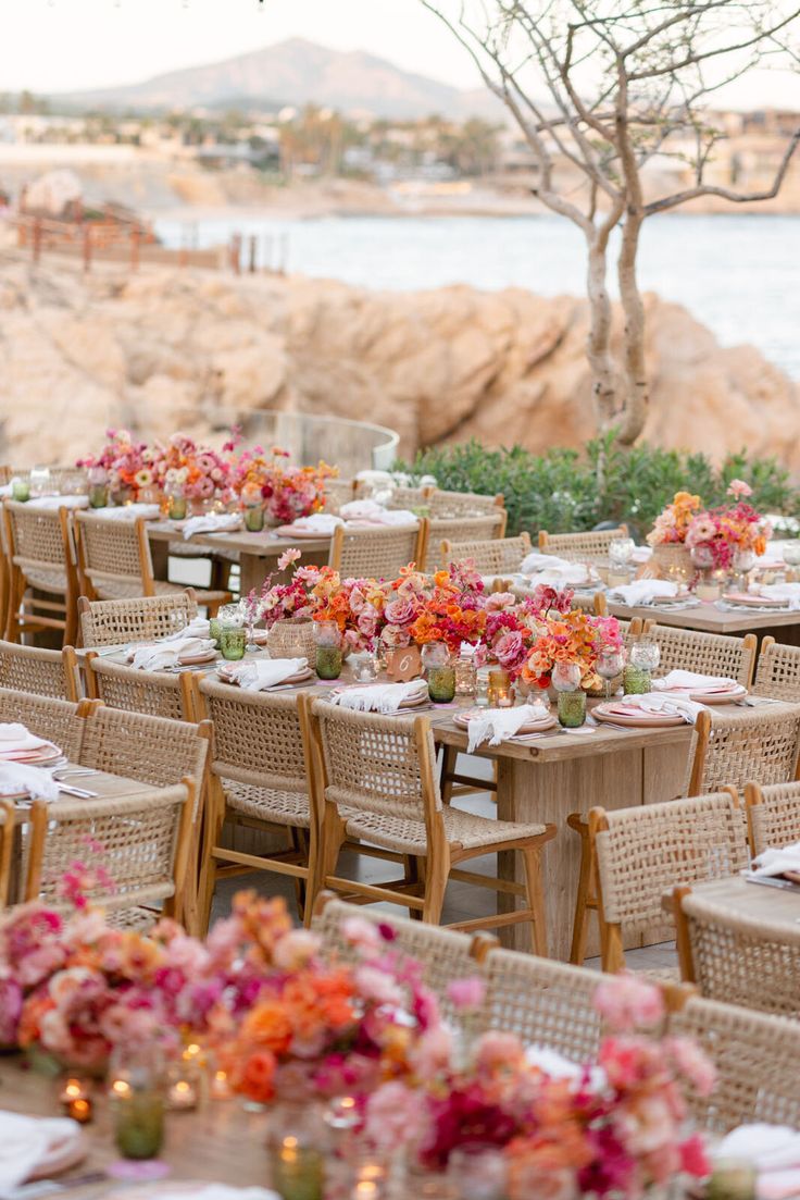 an outdoor dining area with tables, chairs and flowers on the table set for dinner