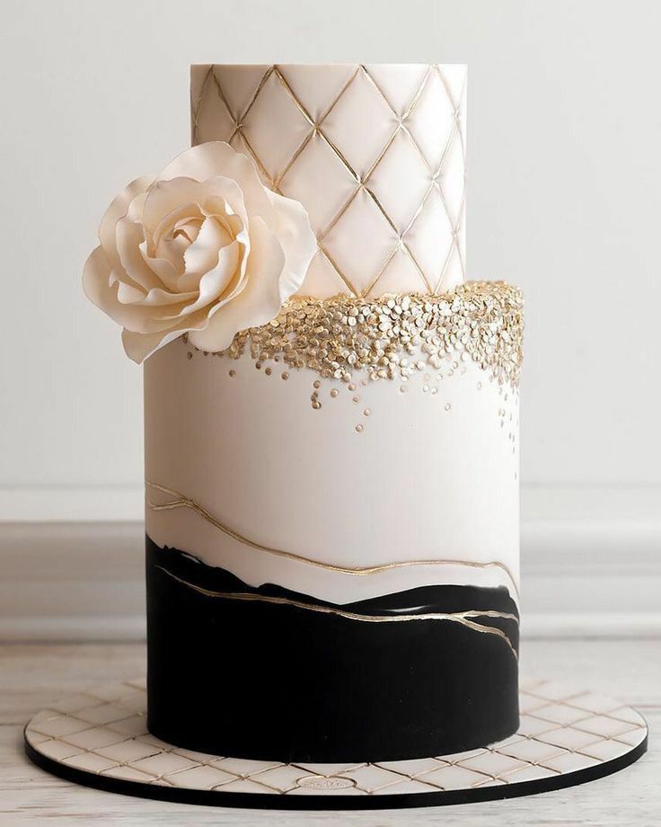 a white and black cake with gold decorations