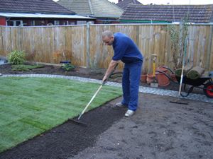 a man is digging in the yard with a lawn mower and grass behind him