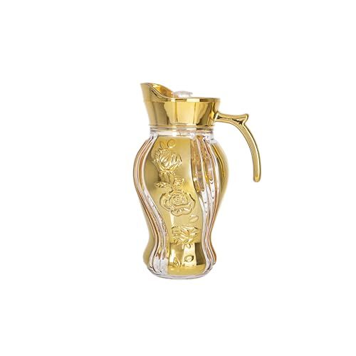 a glass carafe with gold trimmings and a handle on the top, in front of a white background