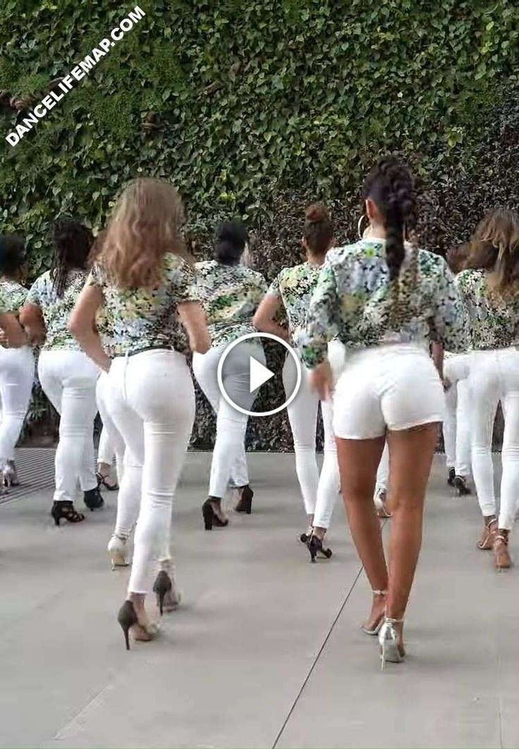 a group of women in white pants and heels walking down the street with their backs to each other