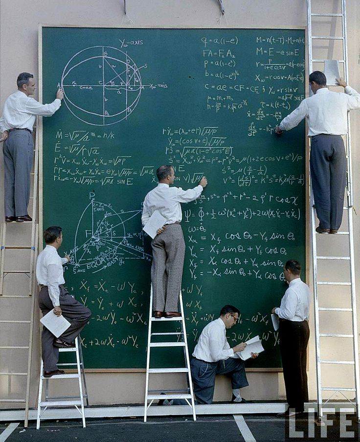 several men standing on ladders writing on a blackboard