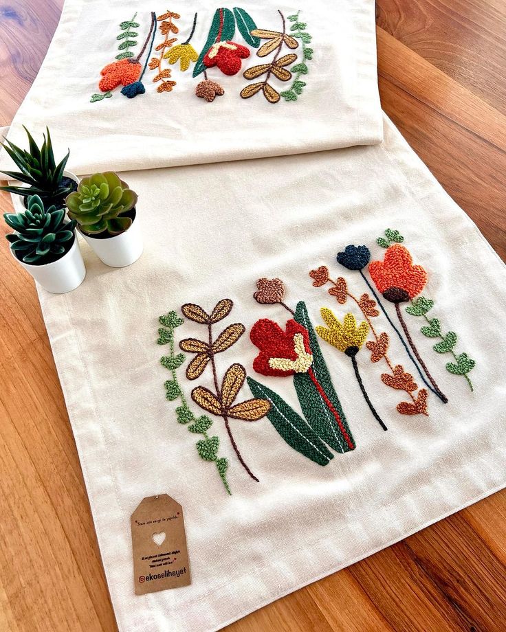 two embroidered tea towels with flowers on them