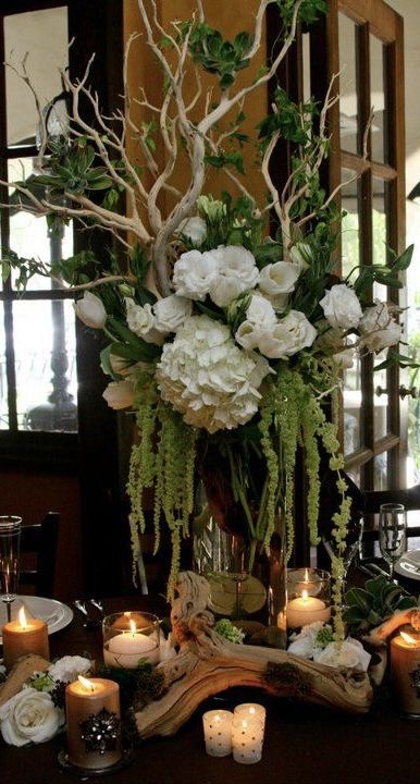 an arrangement of flowers and candles on a table