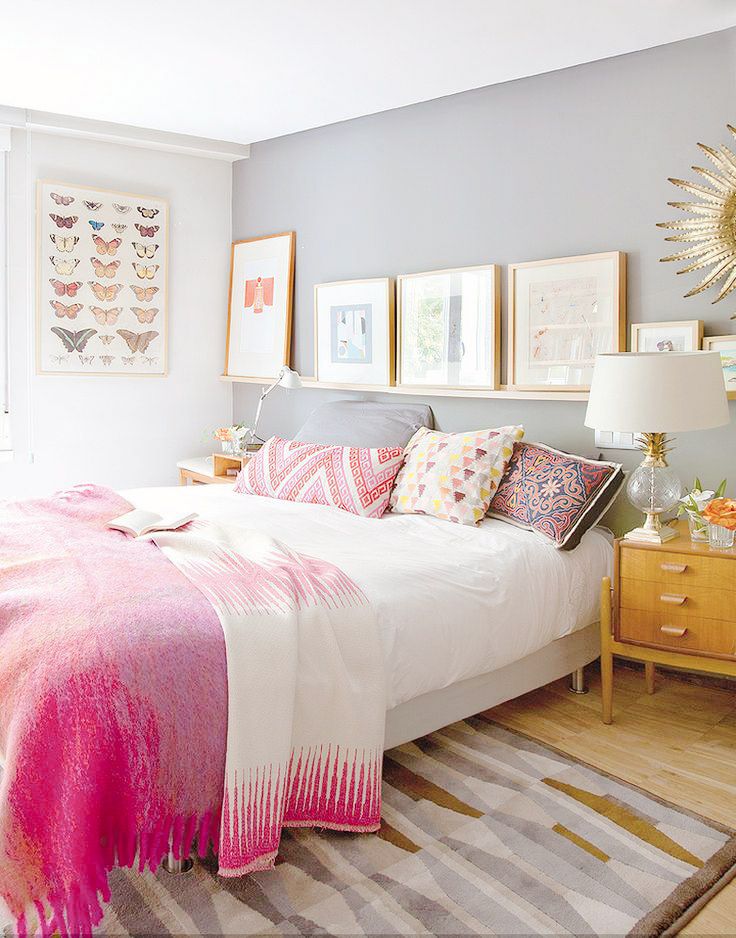 a bedroom with blue walls and pictures on the wall above the bed, along with a pink blanket