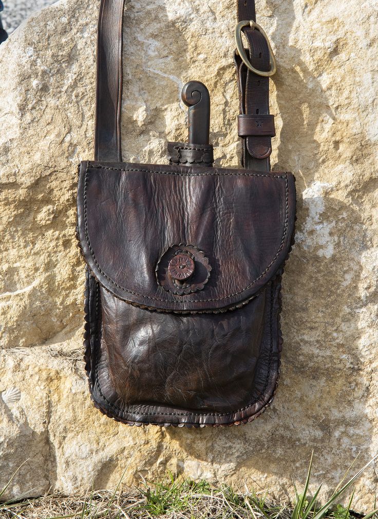 a brown leather purse sitting on top of a rock