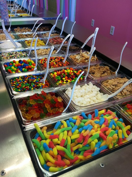 many different types of candy in trays lined up on a buffet table at a restaurant