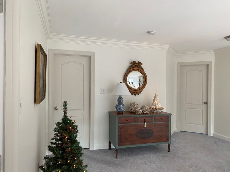 a living room with a christmas tree in the corner and a mirror on the wall