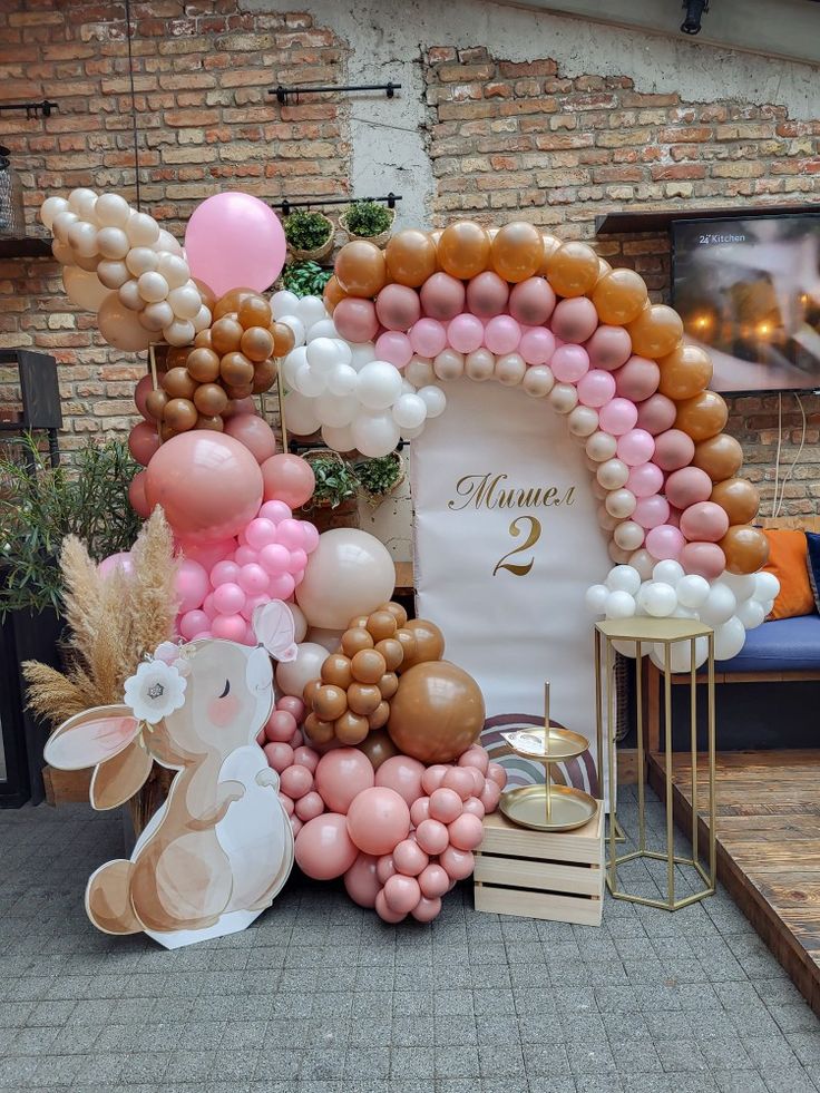 a table topped with balloons and animals next to a sign that says number two on it