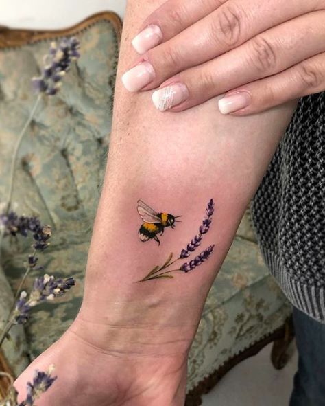 a woman's arm with a bee and lavender tattoo on it