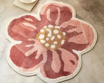 a pink flower rug sitting on top of a floor next to a cup and saucer