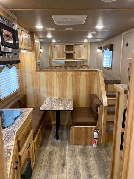 the interior of a travel trailer with wood flooring and cabinets, including a kitchen