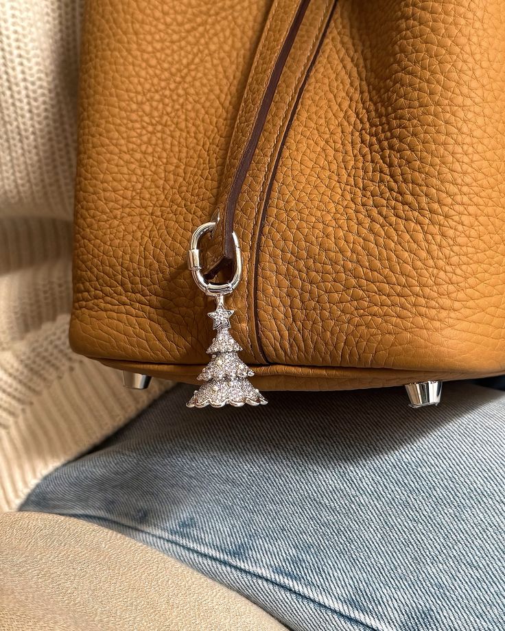 a brown purse with a silver charm hanging from it's side on a couch