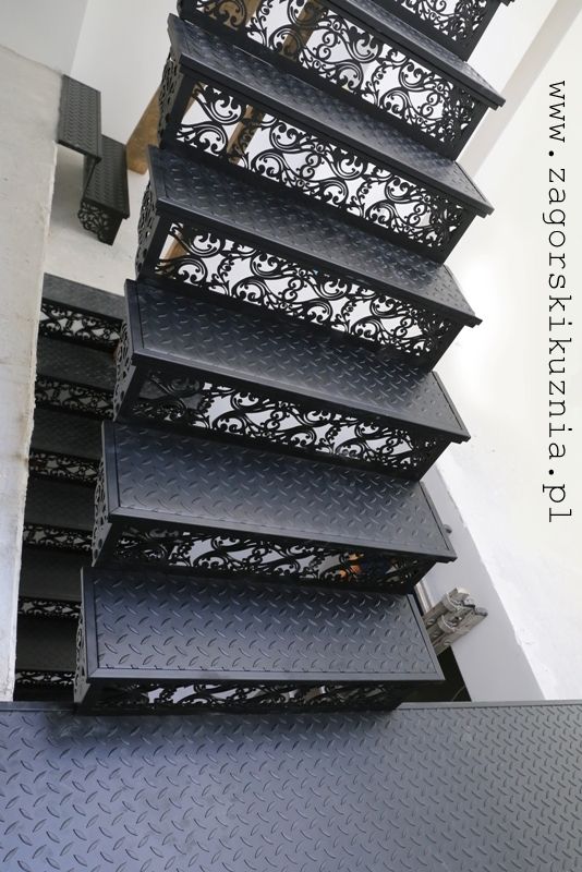 a set of black shelves sitting on top of a metal floor next to a stair case