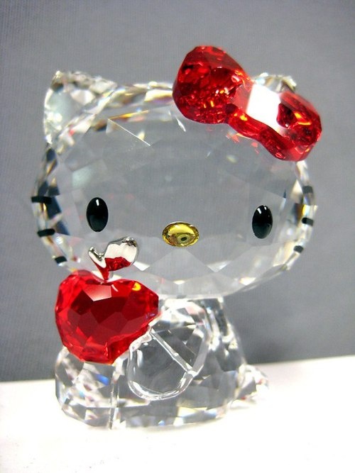 a clear hello kitty figurine with an apple on it's head and eyes