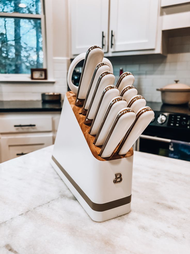 a set of knives sitting on top of a white block in the middle of a kitchen