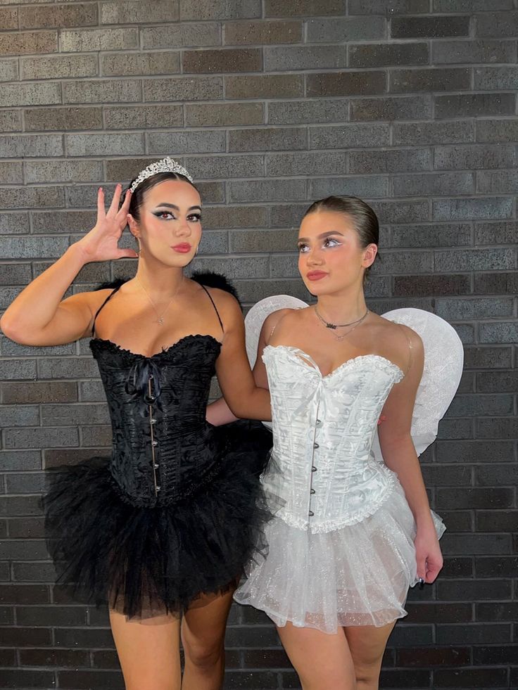 two beautiful young women dressed in costumes standing next to each other with their hands up