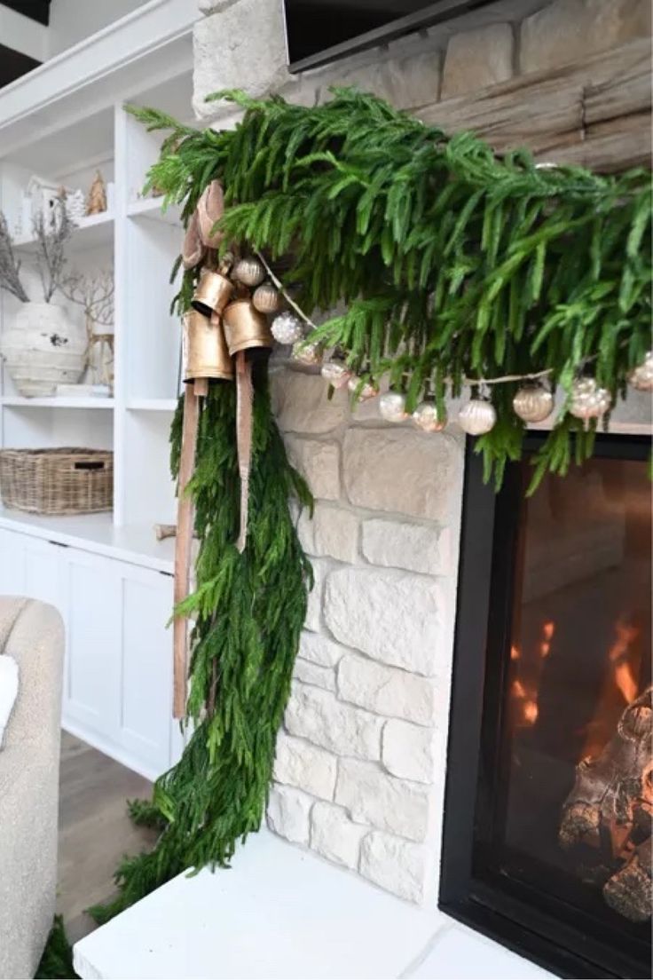 a living room decorated for christmas with greenery and bells hanging from the mantel