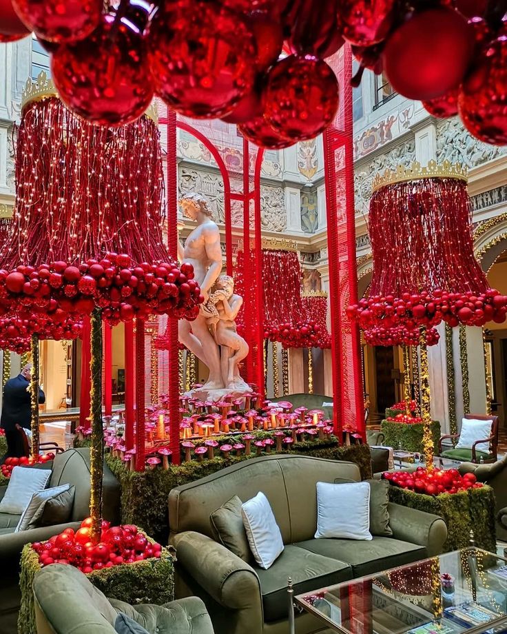 a living room filled with lots of furniture and red balls hanging from the ceiling above