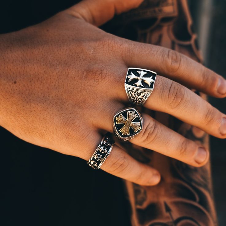 a person's hand with three rings on it and one has a cross in the middle