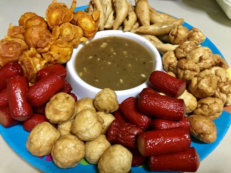 a blue plate topped with lots of different foods and dipping sauces on top of it