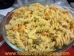 a bowl filled with pasta and vegetables on top of a red tablecloth next to silverware