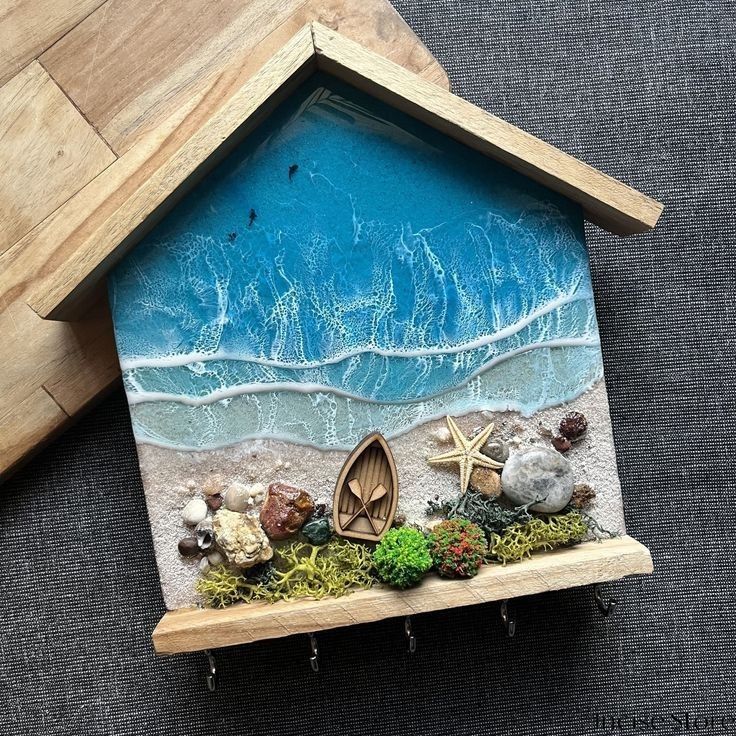 a small house made out of wood and sand with sea shells on the beach inside