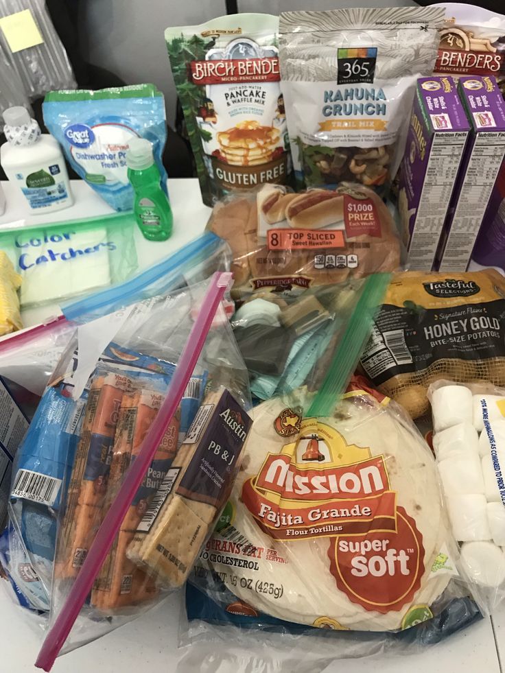 an assortment of food sitting on top of a table next to plastic wrappers and other items