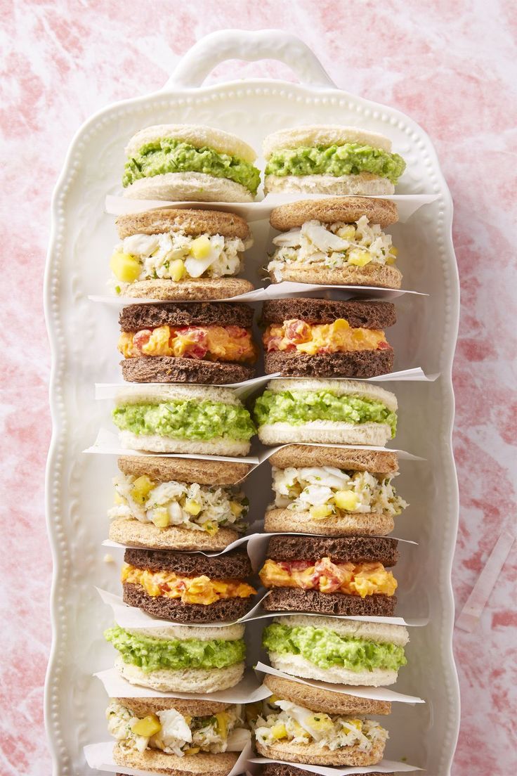 a white plate topped with sandwiches covered in guacamole and other toppings