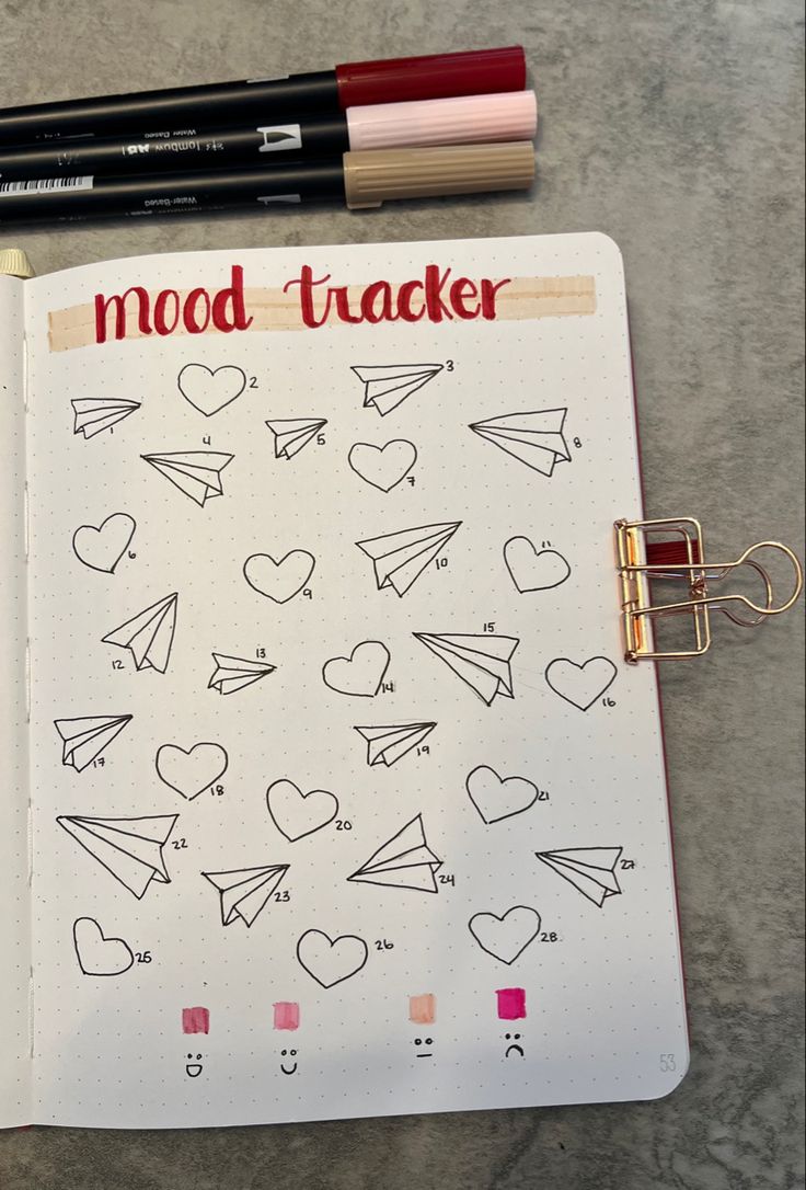 an open notebook with doodles on it next to a pen and marker, which says mood tracker