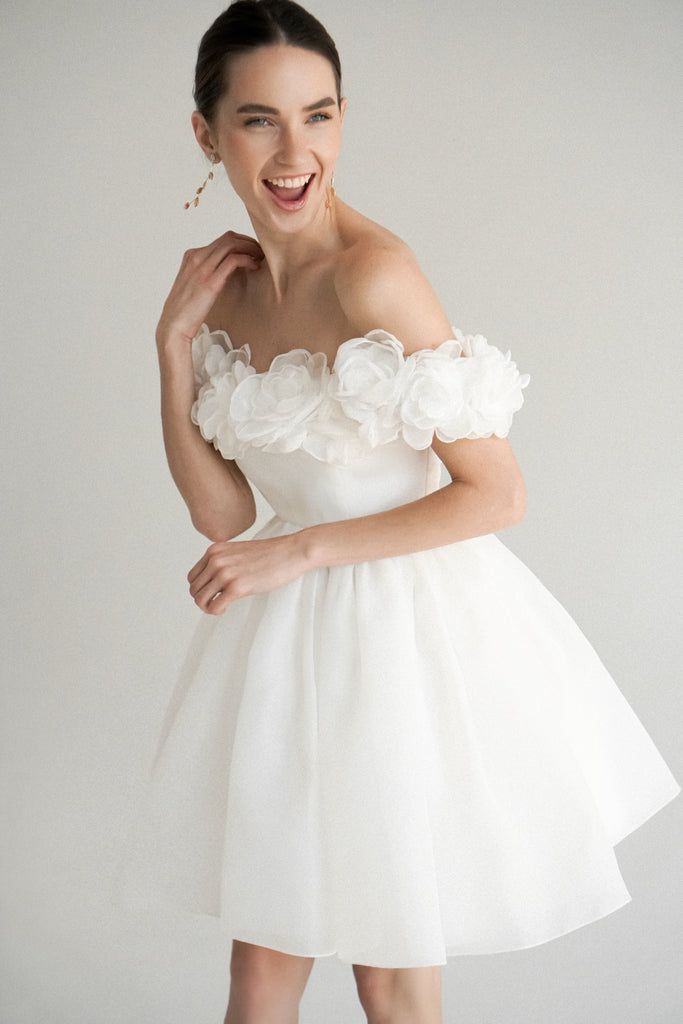 a woman in a white dress posing for the camera with her hand on her shoulder