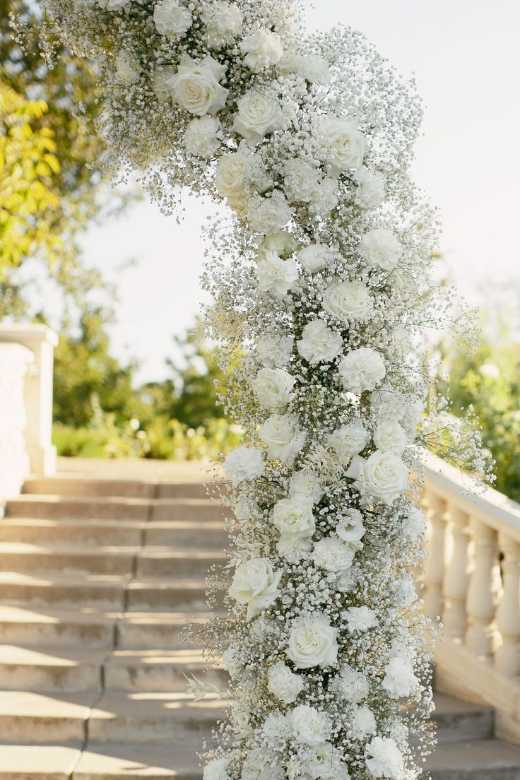 a wedding arch decorated with white flowers and baby's breath