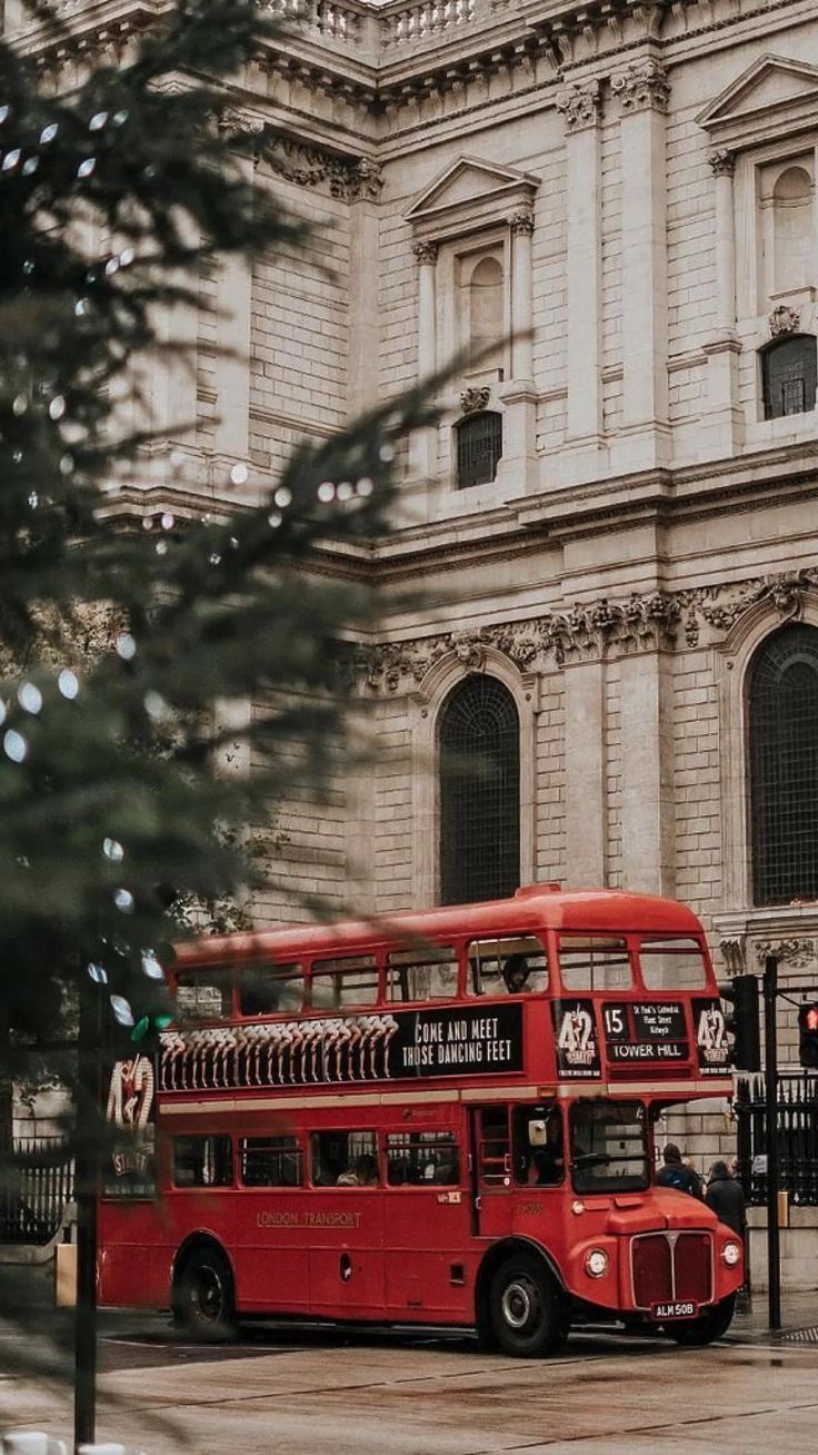 a red double decker bus parked in front of a building