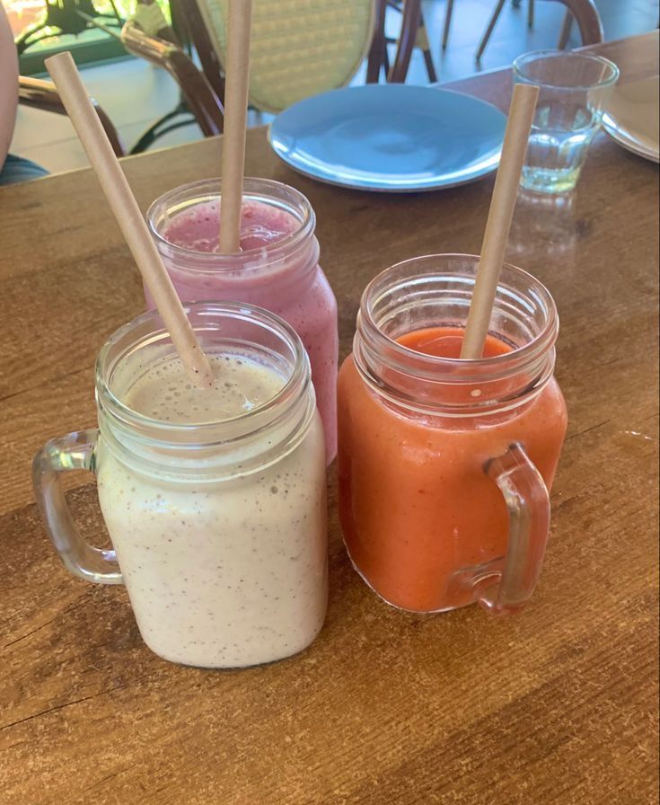 three mason jars filled with smoothies on top of a wooden table next to each other