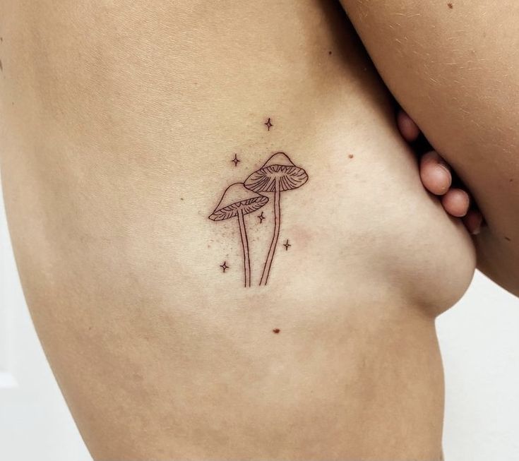 a mushroom tattoo on the back of a woman's right side ribcage