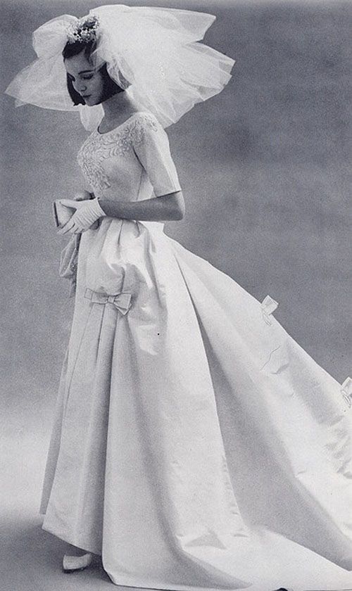 a woman in a wedding dress and veil is posing for a photo with her hand on her hip