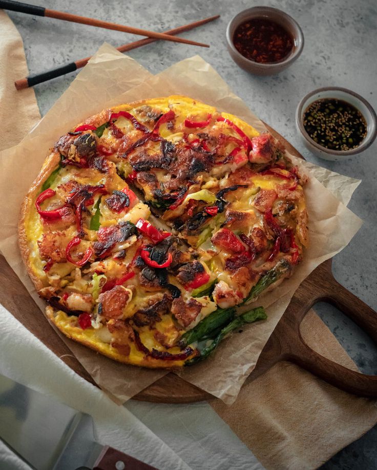 a pizza sitting on top of a wooden cutting board next to some spices and utensils