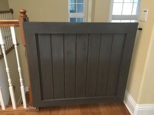 a wooden gate sitting in the middle of a room next to a bannister