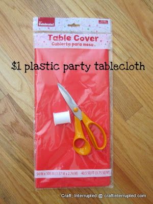 a pair of yellow scissors sitting on top of a plastic party tablecloths bag