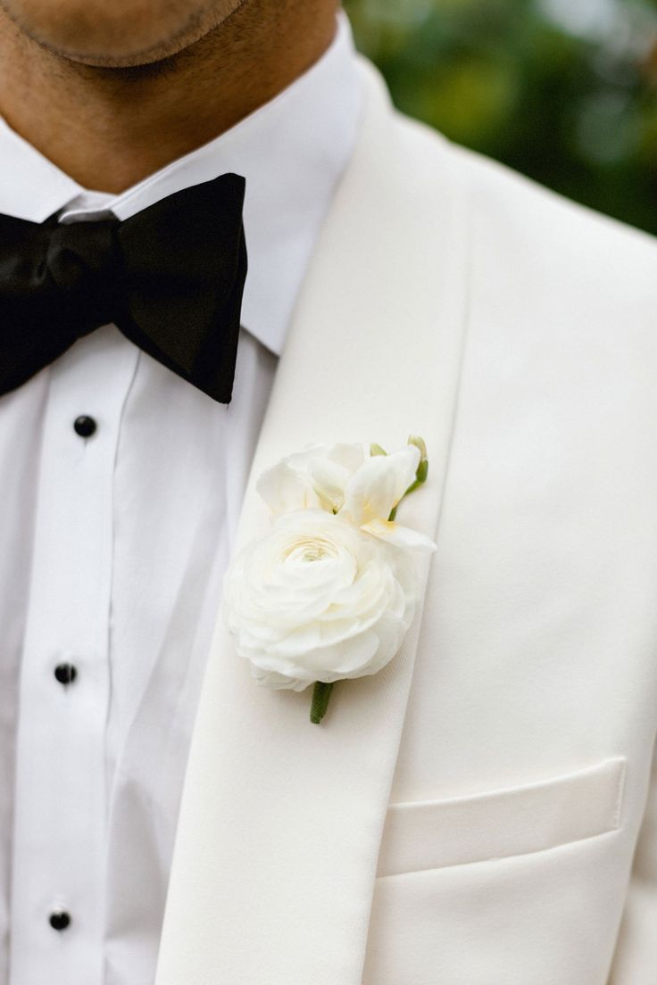 a man in a tuxedo with a white flower on his lapel and black bow tie