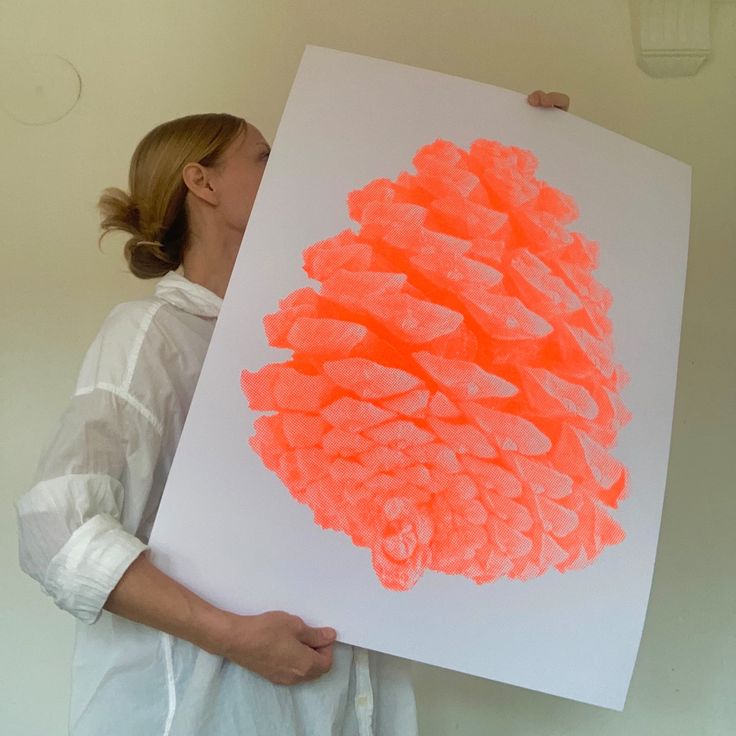 a woman holding up a large piece of art with orange paint on it's surface