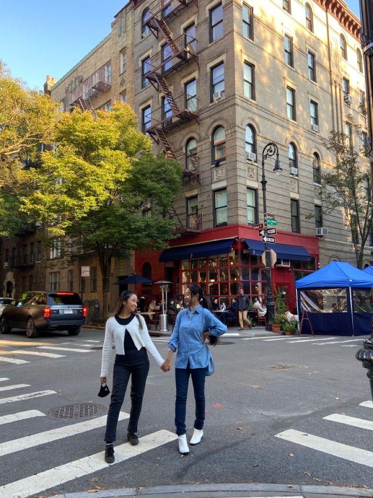 two people walking across the street holding hands