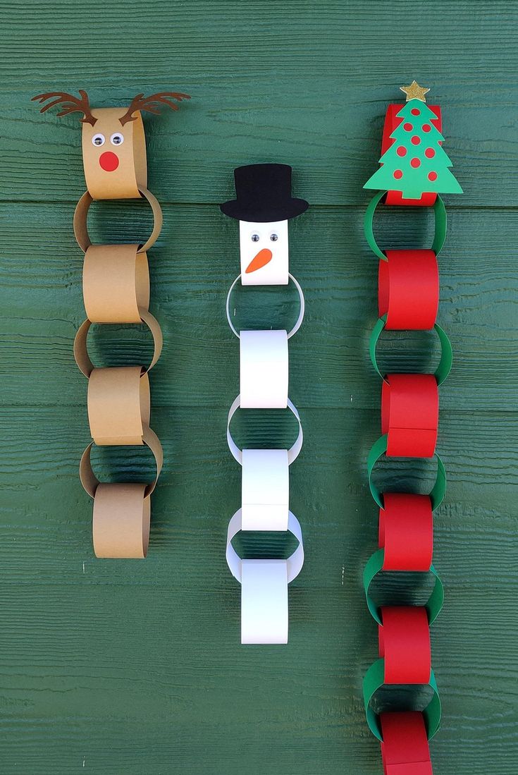 paper roll snowman and reindeer decorations hanging on a green wooden wall with red ribbon