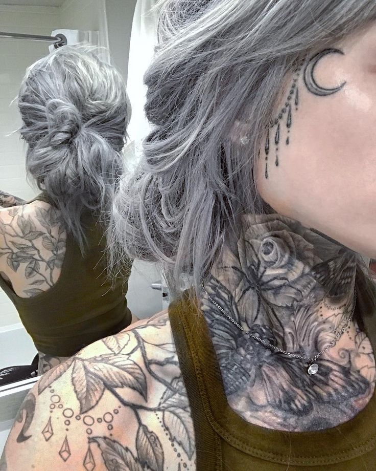 a woman with grey hair and tattoos on her neck