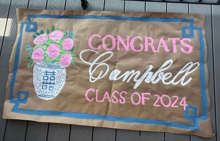 a sign that says congrats campbell class of 2014 with flowers in a vase