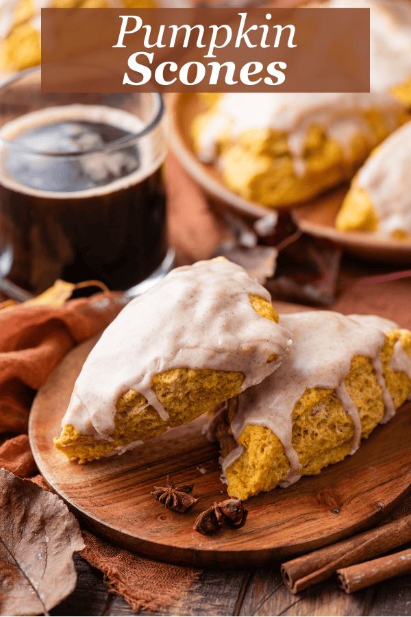 pumpkin scones with white icing on a wooden plate