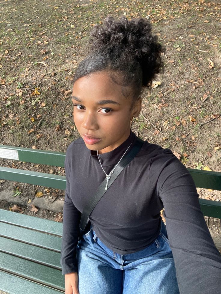 a young woman sitting on top of a green bench