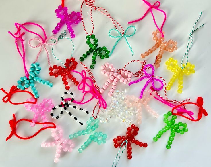 many different colored beads and bows on a white surface with one beaded cross in the middle