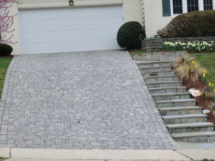 a driveway with steps leading up to the garage door and flowers growing on the side